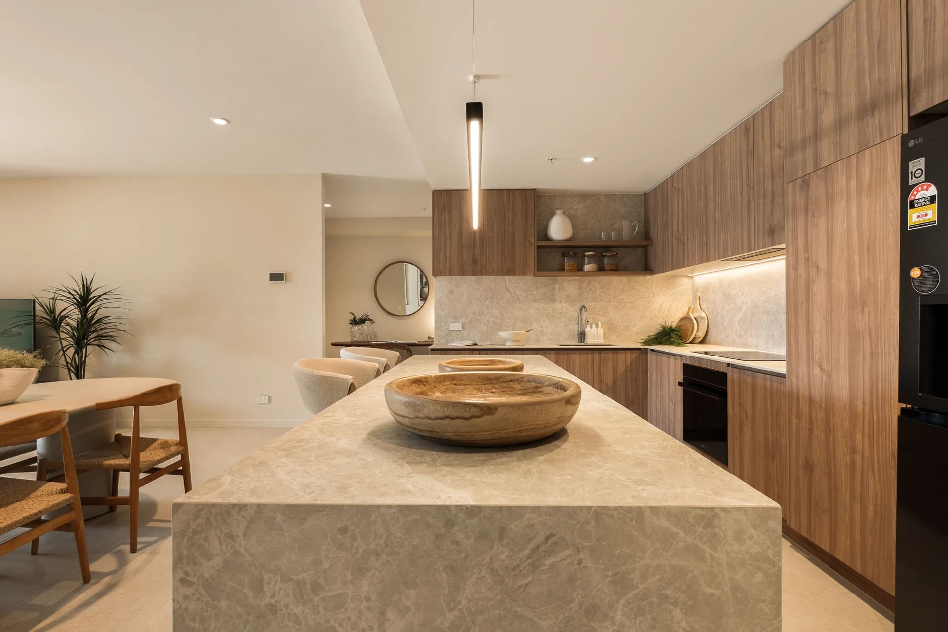 Stone island bench with timber bowls, looking through to the timber-toned kitchen run and stone splashback