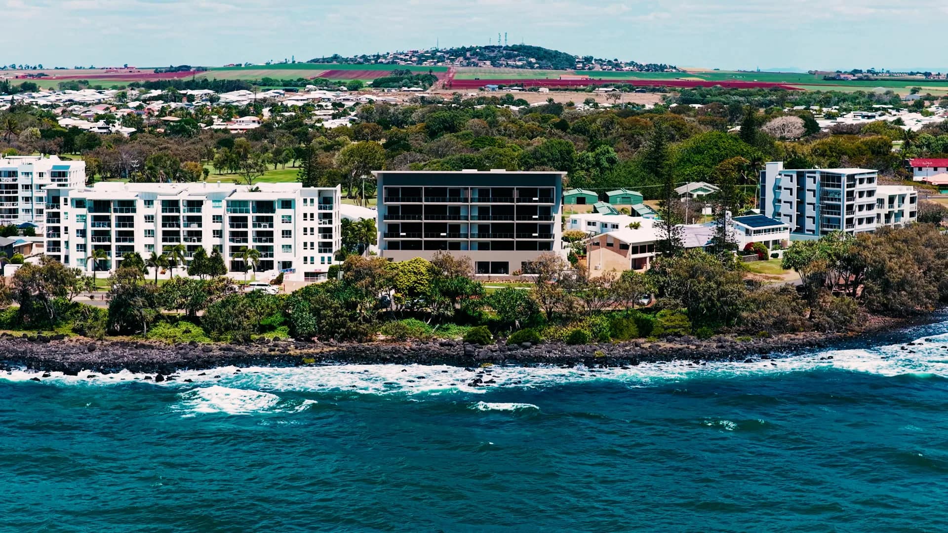 Aerial view of the completed residence on the rocky foreshore, the beach and township of Bargara beyond