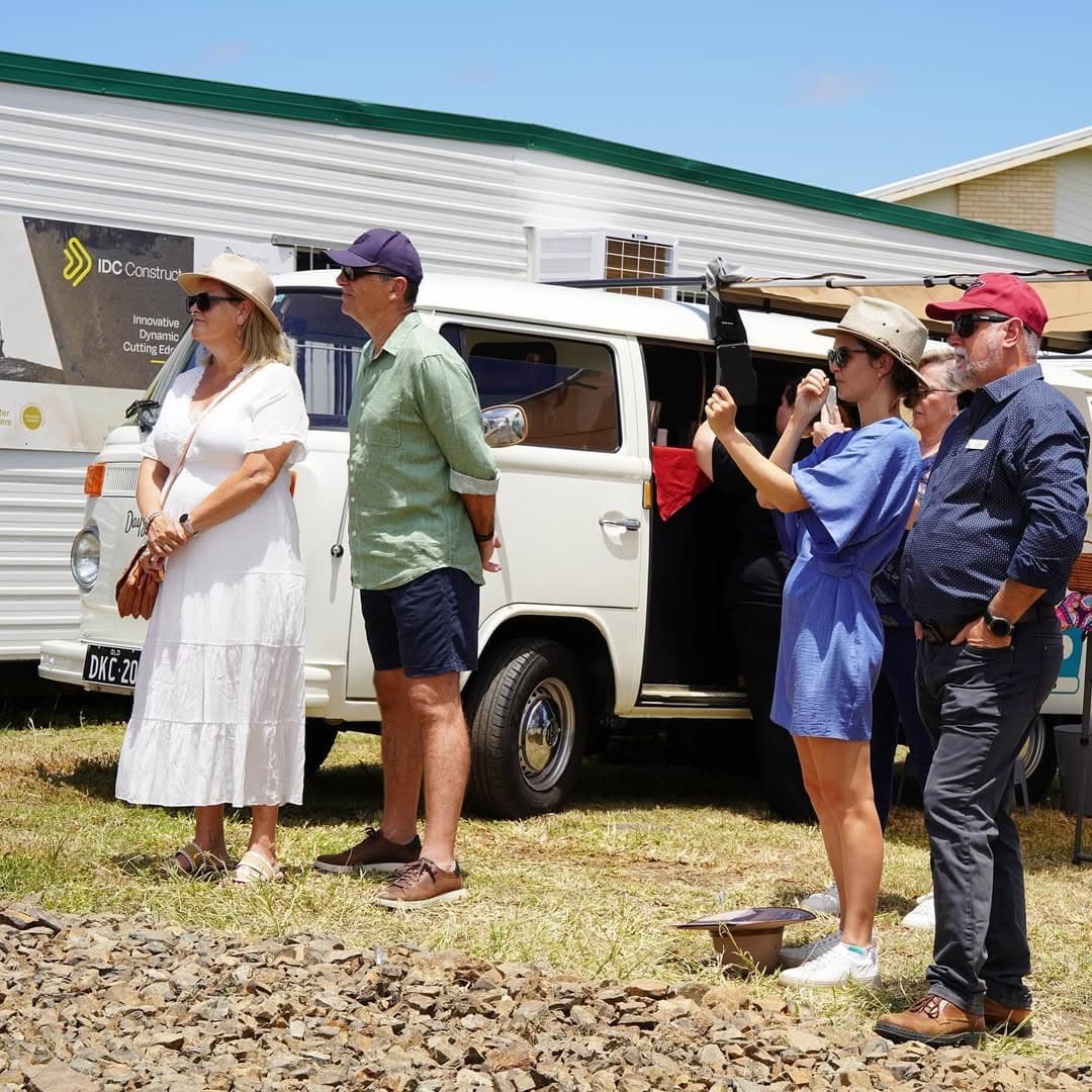 Guests gathered beside a vintage Kombi van at the Mira Living groundbreaking, watching the ceremony on the cleared block